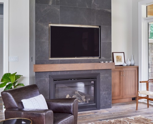 Living room with white baseboard, built in tv and wood cabinet.