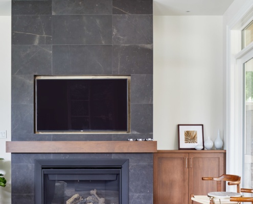 Family room with stone fireplace, wood mantle and floor to ceiling window.