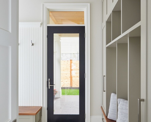 Mud room with white wall, wood bench and back door.