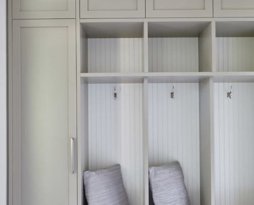 Mud room with gray cubby, tile floor and white baseboard.