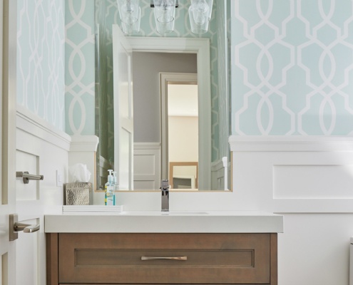 Bathroom with floating vanity, wainscoting and blue wallpaper.