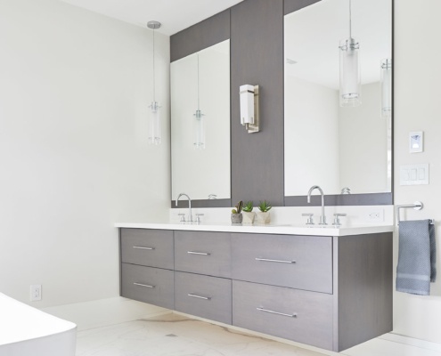 Modern master bathroom with wood floating vanity, tile floor and pendant lights.