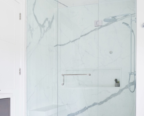 Master bathroom with marble tile, glass shower and white trim.