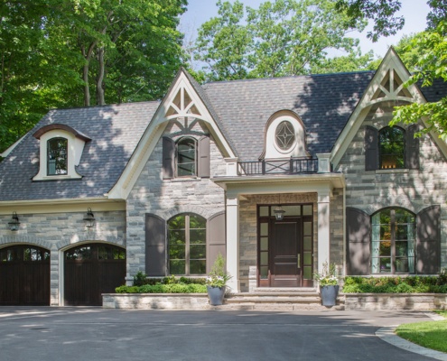 Custom home with glass railing, shingled and natural stone wall.