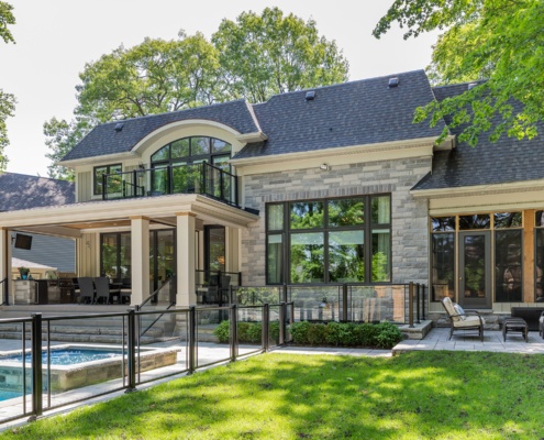 Home rear exterior with inground pool, white trim and stucco siding.