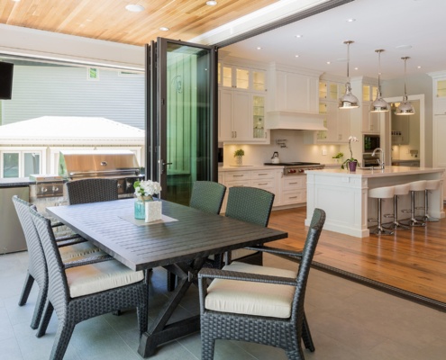 Stone patio with wood ceiling, outdoor kitchen and large sliding glass door.