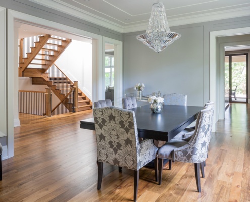 Dining room with hardwood floor, crystal chandelier and white crown moulding.