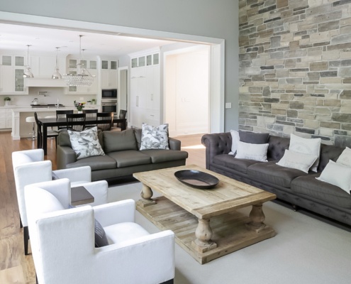 Family room with stone wall, wood coffee table and white trim.
