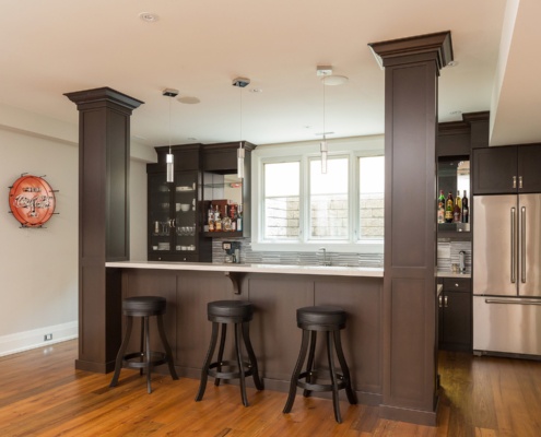 Modern kitchen with dark cabinetry, tile backsplash and large island.