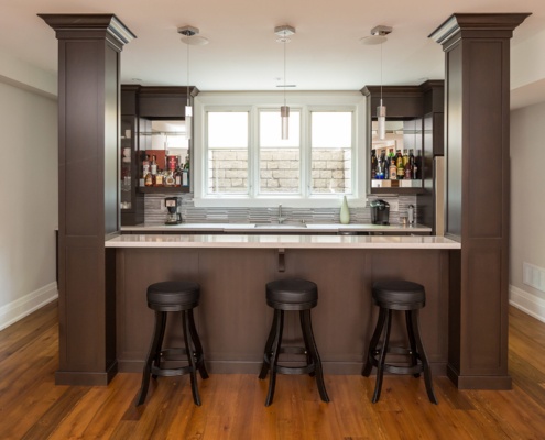 Home bar with dark wood, hard wood floor and white baseboard.