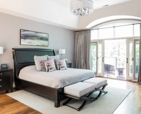 Master bedroom with white frame windows, hardwood floors and chandelier.