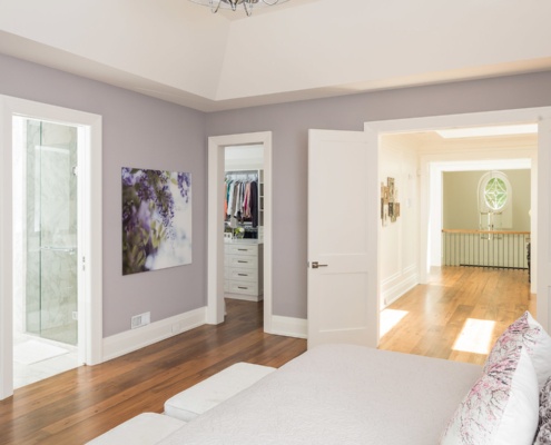 Master bedroom with hardwood floor, white baseboard and vaulted ceiling.