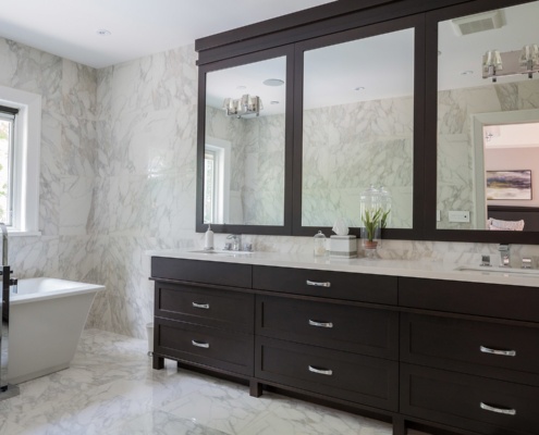 Tiled bathroom with dark vanity and white frame window.