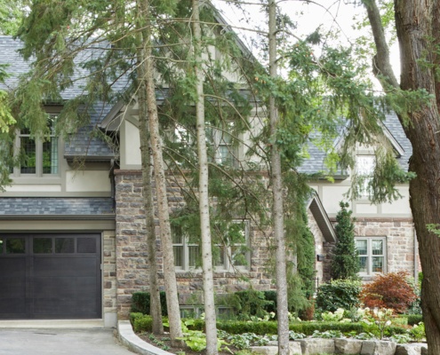 Tudor home with wood garage door, natural stone and stucco siding.