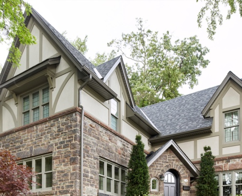 Tudor style home with natural stone, gables and shingled siding.