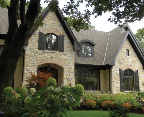 Traditional home with natural stone, dark shutters and black frame windows.