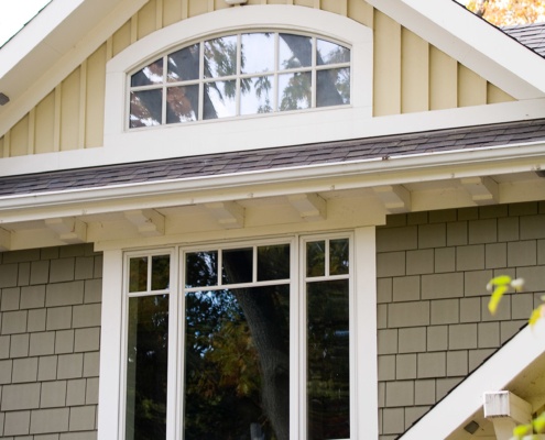 Custom home with green stucco and shingled roof.