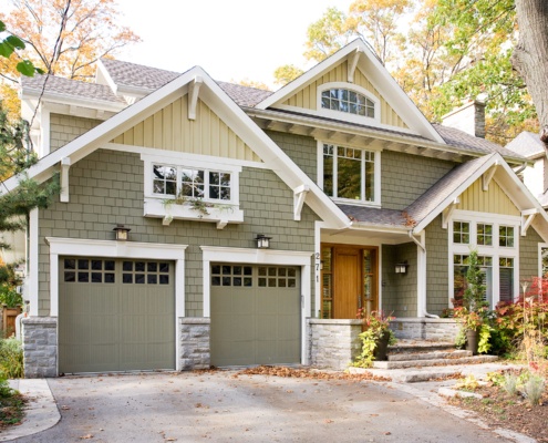 Traditional home with wood front door, white brackets and stone siding.