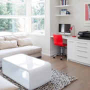 Den with white windows, floating shelves and hardwood floor.