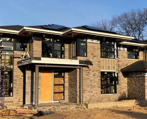 Construction of natural modern home with black frame windows.