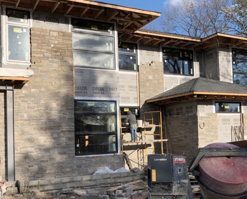 New York house under construction with natural stone and floating roof.