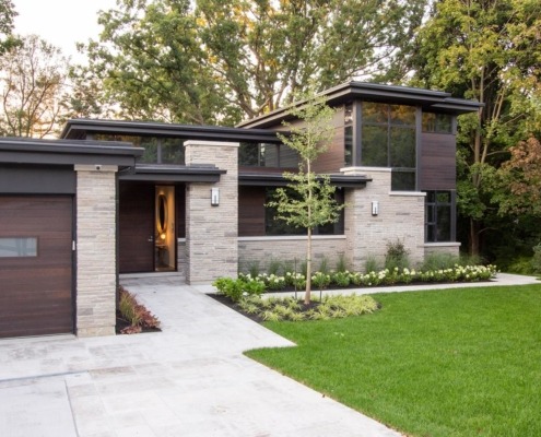 Modern bungalow with natural stone, flat roof and black frame windows.