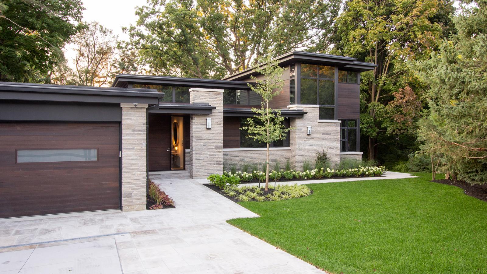 Modern bungalow with natural stone, flat roof and black frame windows.