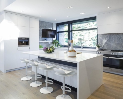 Modern kitchen with white cabinets, stone backsplash and stainless steel oven.