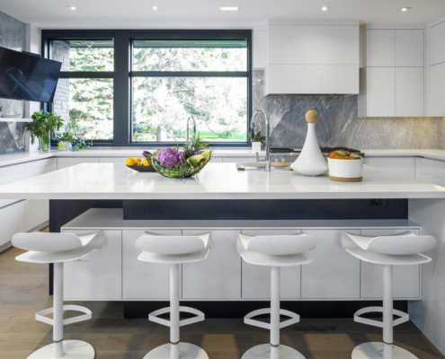 White kitchen with breakfast bar, black frame window and white countertop.
