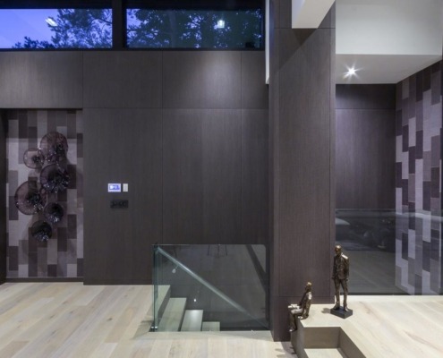 Modern interior with floating staircase, hardwood floor and wood wall.