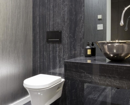 Bathroom with wallpaper, bowl sink and white baseboard.