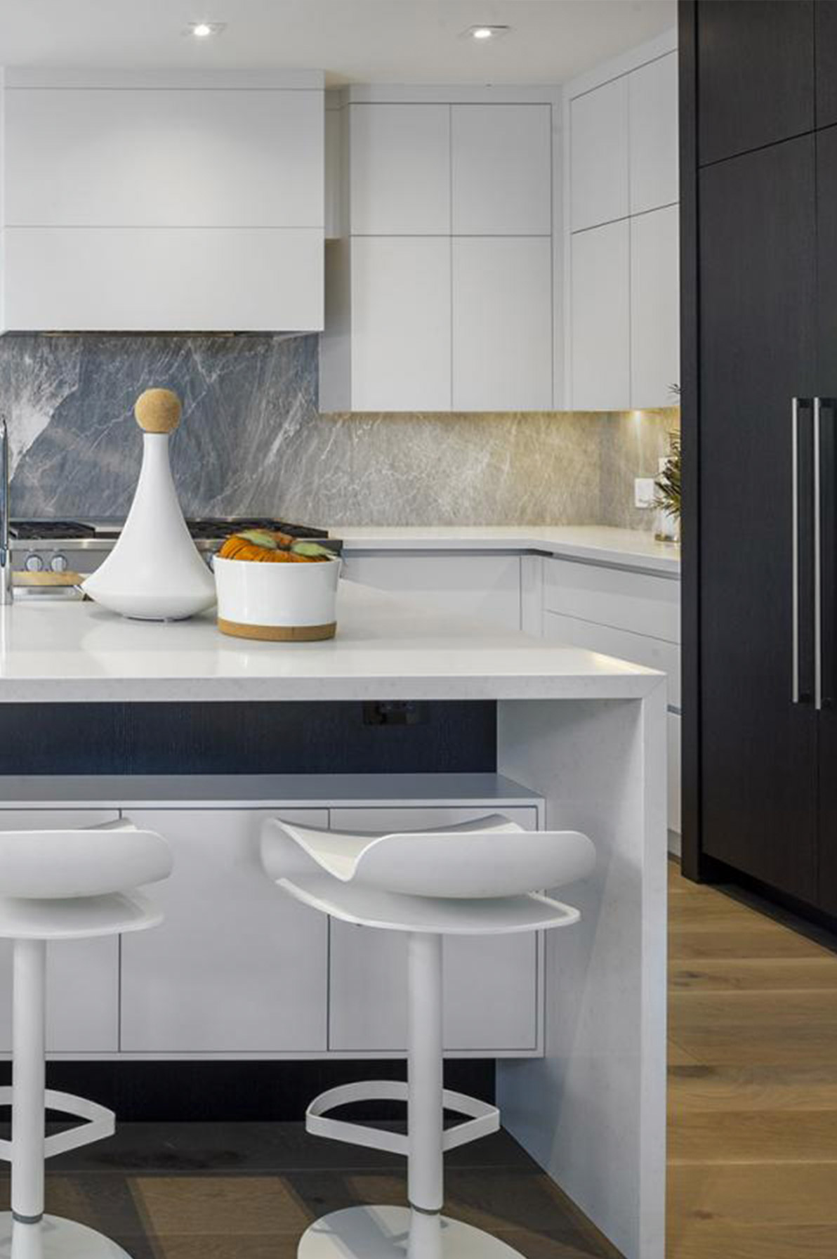 Modern kitchen with white cabinets, stone backsplash and breakfast bar.