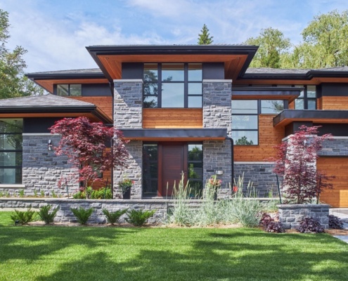 Modern home with wood front door, corner windows and floating roof.