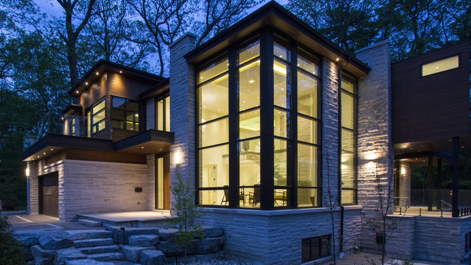 Natural modern house with light stone, wood siding and corner windows.