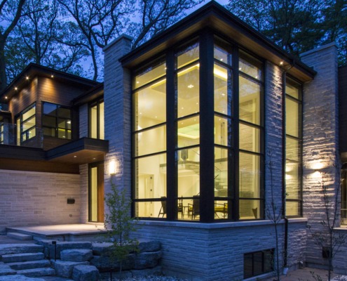 Natural modern house with light stone, wood siding and corner windows.