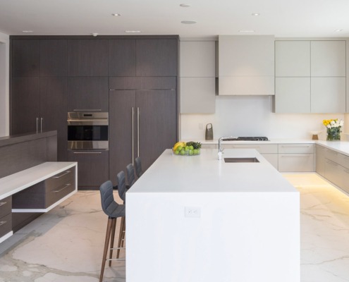 Kitchen with white island, dark cabinets and large windows.
