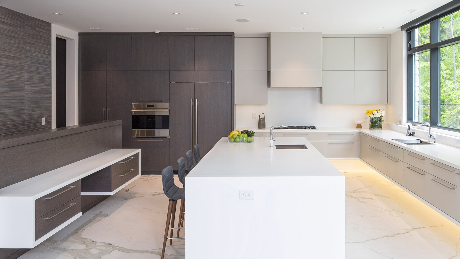 Kitchen with white island, dark cabinets and large windows.