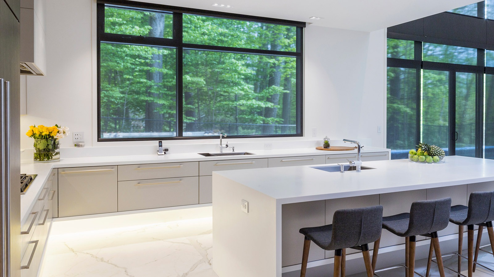 Modern kitchen with gray drawers, black frame windows and white island.