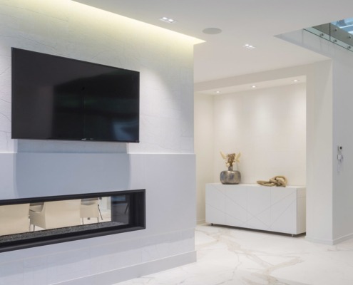 Modern house with double sided fireplace, marble floor and white baseboard.