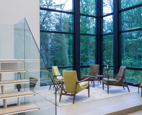 Living room with green chair, exposed stone and black frame windows.