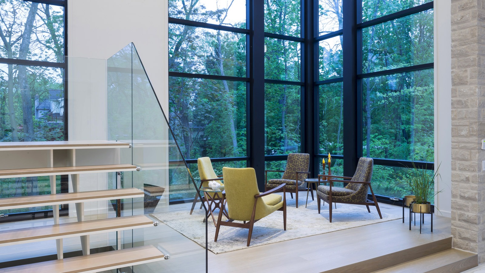 Living room with green chair, exposed stone and black frame windows.