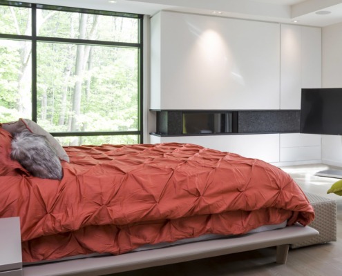 Modern bedroom with black frame window, white cabinets and hardwood floor.