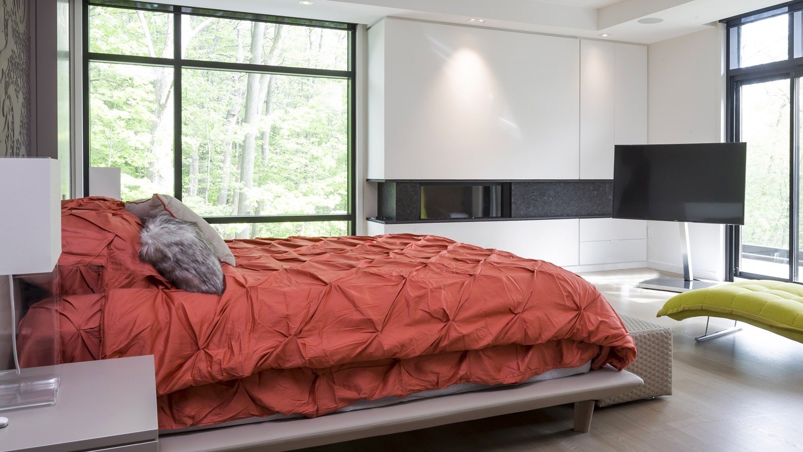 Modern bedroom with black frame window, white cabinets and hardwood floor.