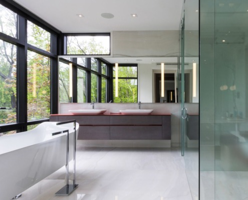 Master bathroom with freestanding tub, floating vanity and large windows.