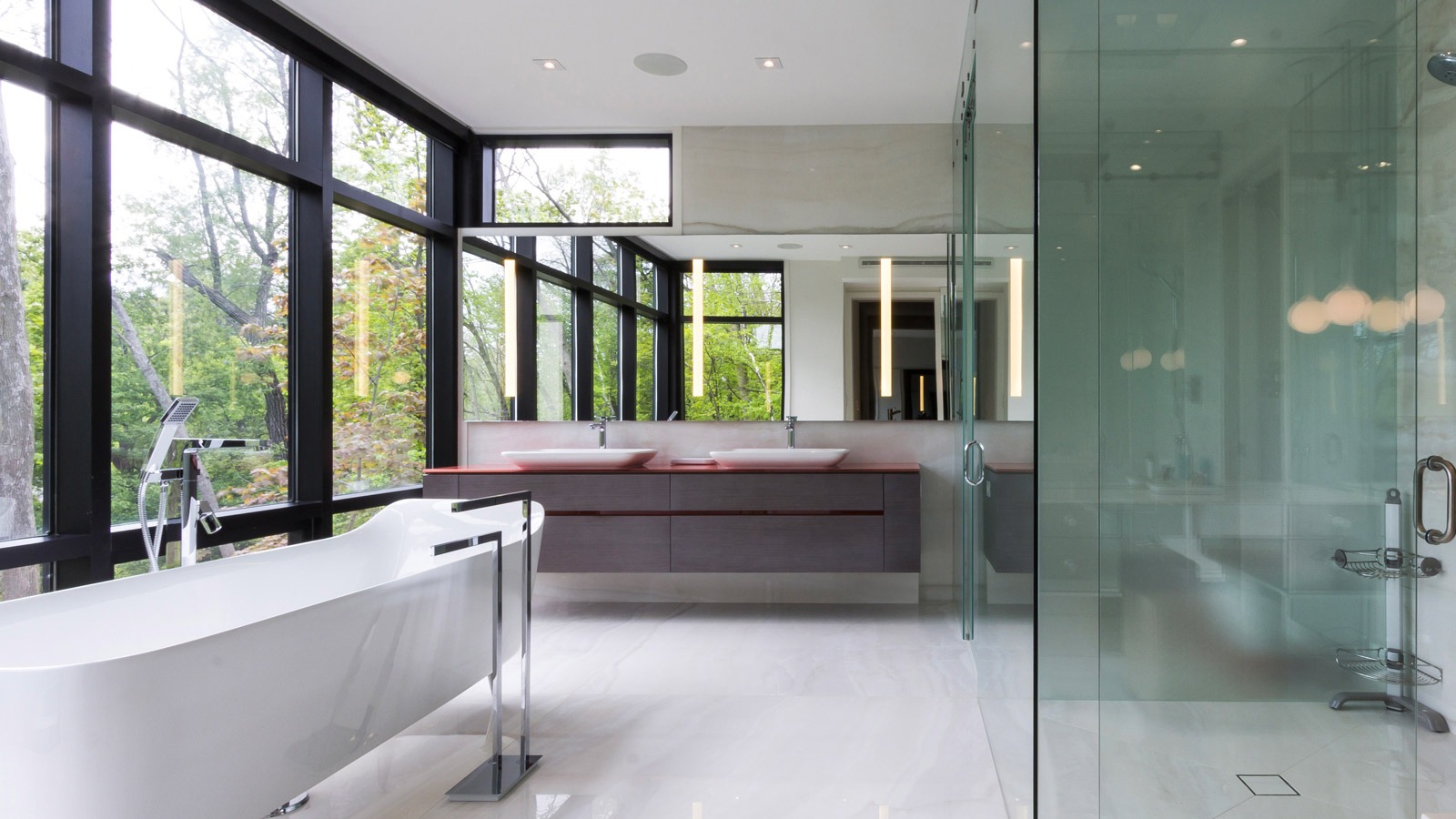 Master bathroom with freestanding tub, floating vanity and large windows.