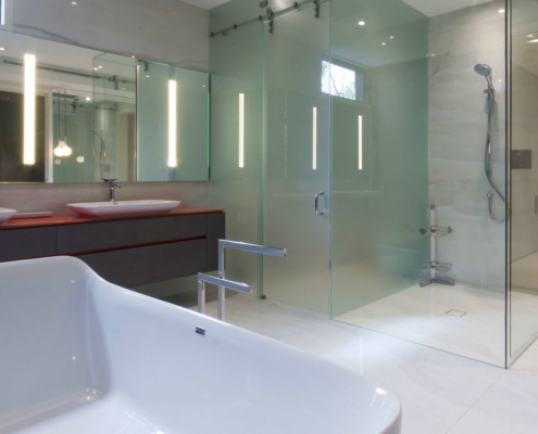 Modern bathroom with double sinks, glass shower and tile floor.