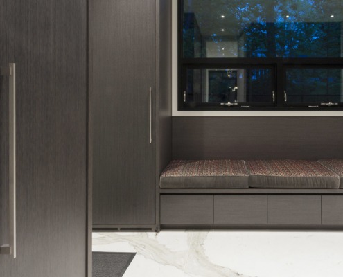 Dressing room with wood cabinets, black frame windows and marble floor.