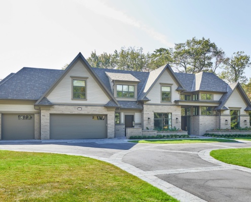 Traditional home with 3 car garage, shingled roof and natural stone.