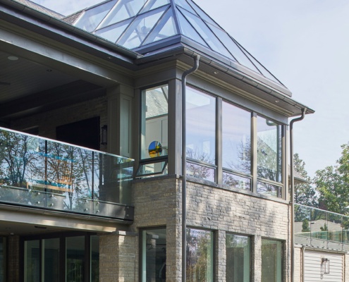 Custom home with glass sunroom, black frame windows and glass railing