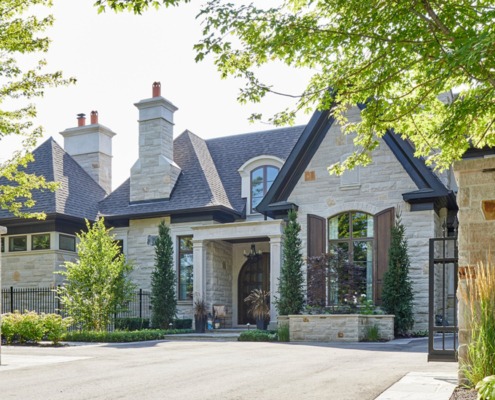 Luxury home with natural stone, iron gate and wood shutters.